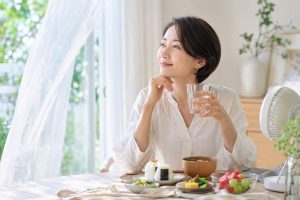 夏の明るい室内で、軽い食事と水分を取りながら穏やかに休む50歳前後の日本人女性