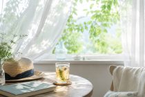 夏の光が差し込む窓辺で、ハーブティーと本、麦わら帽子を置いて静かに過ごす夏の暮らし